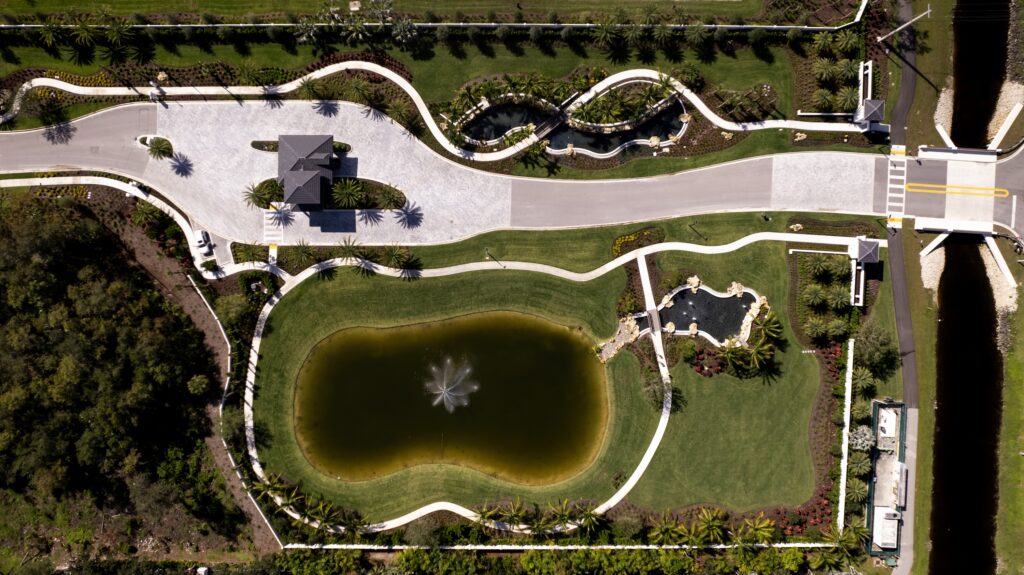 Alternative aerial angle of Caymas Naples waterfront homes with private docks, kayaks on the lake, scenic walking trails winding through preserves, luxury estates with expansive lanais, photorealistic 8K, golden hour lighting