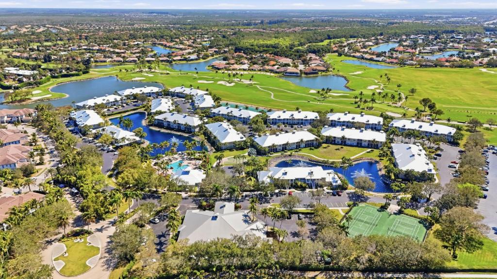 Aerial perspective of Lely Resort community showing multiple neighborhoods, golf courses, and amenities with Marco Island in the distance, photorealistic 8K, clear blue sky