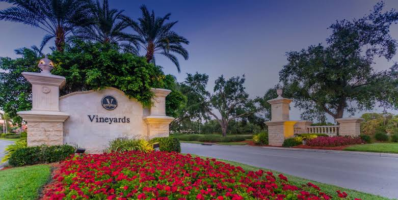 Photoreal 8K studio hero shot of The Vineyards Country Club entrance at golden hour, elegant stone and palm-lined driveway, clean centered composition on premium dark gradient background, luxury real estate photography