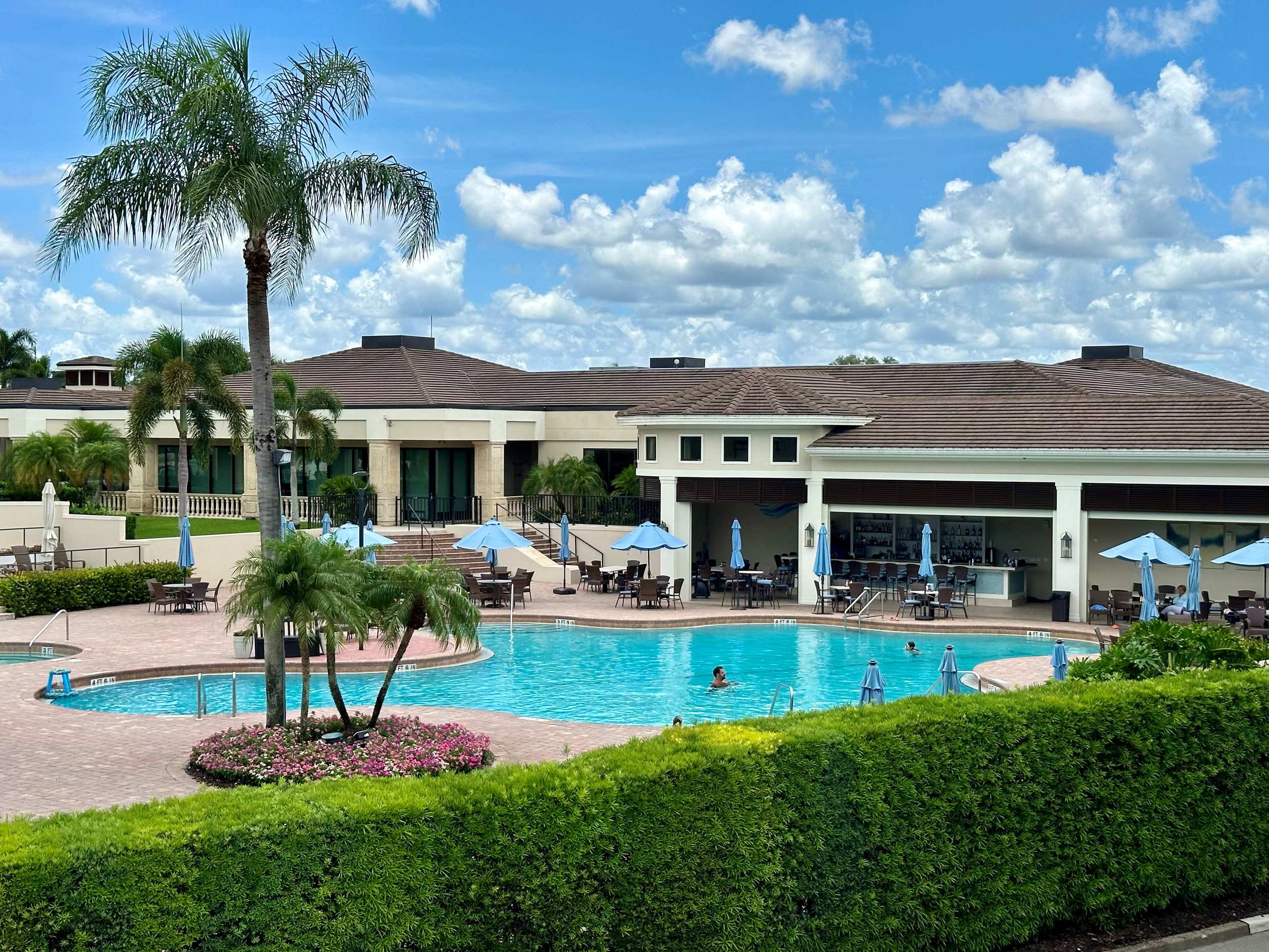 Lifestyle 8K image of residents enjoying the community pool at sunset with palm trees and clubhouse in background, natural lighting, photorealistic detail