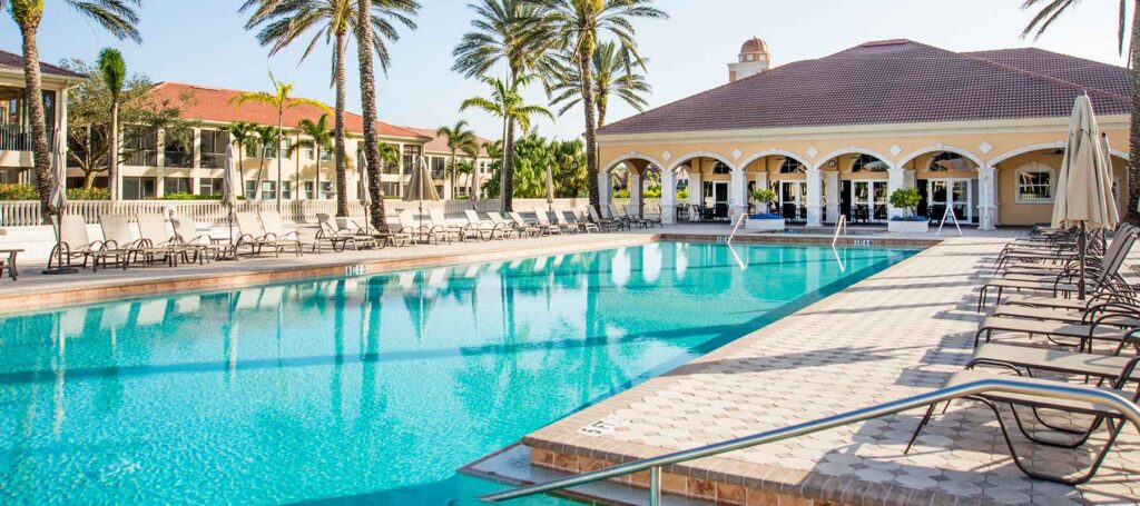 Interior 8K lifestyle shot of the 70,000-sf clubhouse lounge area with members, elegant furnishings and large windows overlooking the course