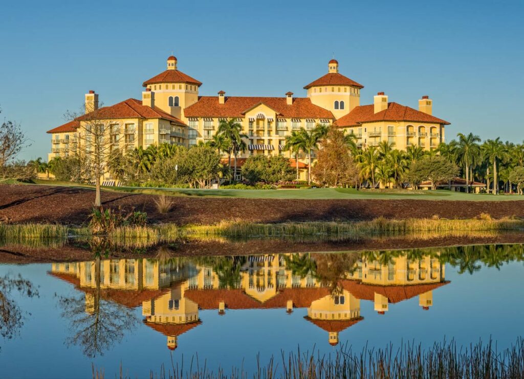 Lifestyle 8K image of golfers on the 18th green of the Gold Course at Tiburón with the Mediterranean clubhouse in background, sunset lighting, premium resort photography